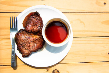 A hot pork steak is placed on a white plate.