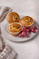 Vertical orientation cupcakes with cherries and grapes on plate with napkin on light background