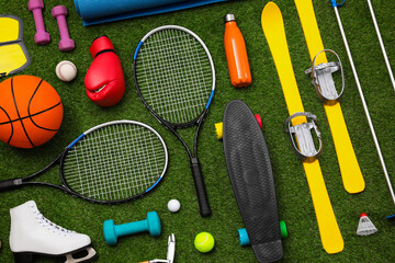 Different sport equipment on green grass, flat lay