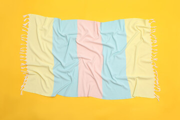 Crumpled striped beach towel on yellow background, top view
