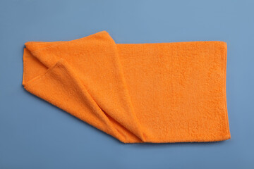 Folded orange beach towel on blue background, top view