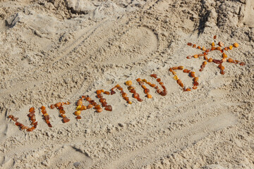 Inscription vitamin D with shape of sun on sand at beach. Prevention of vitamin D deficiency. Summer and vacation time