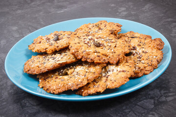 Fresh baked oatmeal cookies with honey and healthy seeds on blue glass plate. Delicious crunchy dessert