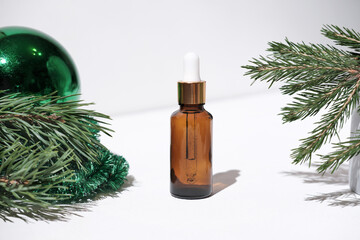 Fototapeta premium Christmas minimalistic composition with amber glass serum or oil bottle . skin health and beauty concept