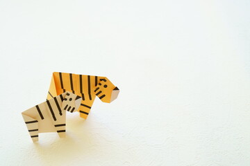 白い背景に折り紙の右を向いた2頭の黄色い虎とホワイトタイガー