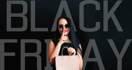a beautiful customer with a shopping bag in her hands and wearing dark glasses, isolated on a black...