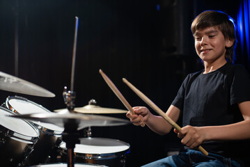 A boy plays drums in a recording studio