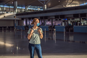 Woman in mask at empty airport at check in in coronavirus quarantine isolation, returning home,...