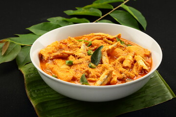 Delicious homemade  anchovy fish curry with coconut and green mangoes - Asian seafood recipes background.