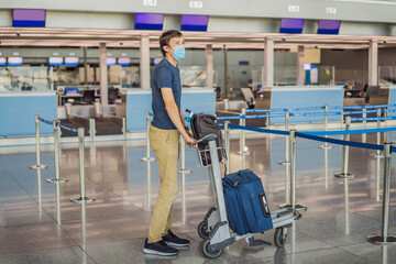 Man in mask at empty airport at check in in coronavirus quarantine isolation, returning home, flight cancellation, pandemic infection worldwide spread, travel restrictions and border shutdown