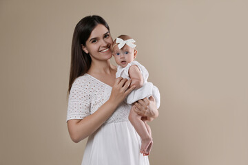 Beautiful mother with her cute baby on beige background