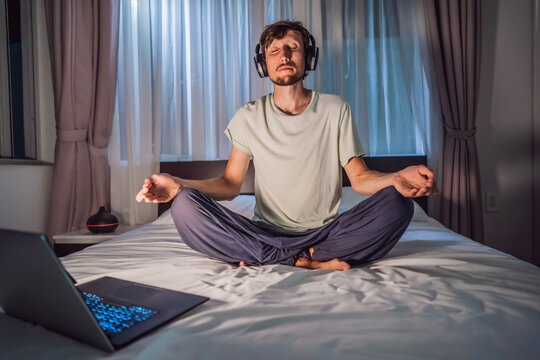 Man Meditates On Bed Using Meditation App. Sport, Technology And Healthy Lifestyle Concept