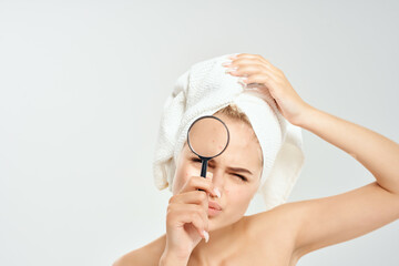 woman with bare shoulders holding a magnifying glass near face dermatology clear skin
