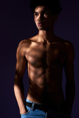 Fototapeta na wymiar African american male in shadow standing in studio with purple background verticale portrait shot