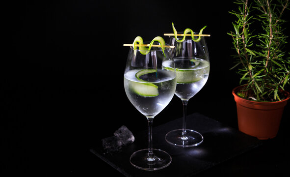 two gin tonc with cucumber and rosemary on a balck background