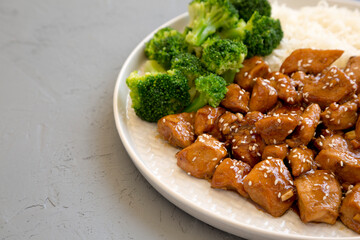 Homemade Teriyaki Chicken with Rice and Broccoli on a plate on a gray background, side view. Space for text.