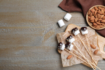 Delicious marshmallows covered with chocolate on wooden table, flat lay. Space for text