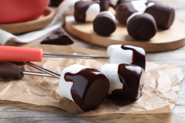 Delicious marshmallows covered with chocolate on wooden table, closeup