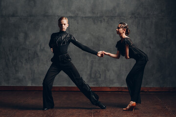 Couple young man and woman in black dress dancing in ballroom dance rumba