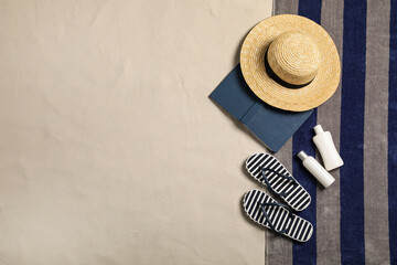Beach towel, hat, book, sun protection products and flip flops on sand, flat lay. Space for text - obrazy, fototapety, plakaty