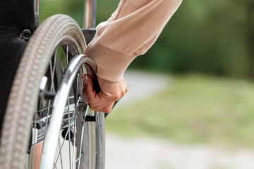 Close-up of a hand on a wheelchair wheel. The concept of a wheelchair, disabled person, full life,...