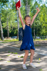 Joyful schoolgirl jumping outdoors. End of summer vacation and start of the primary school year