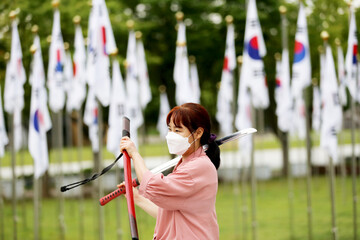 Korean woman practicing kendo in a hi-dong kendo pose with a sword