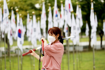 Korean woman practicing kendo in a hi-dong kendo pose with a sword