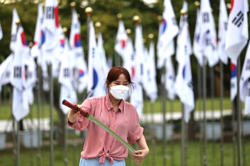 Korean woman practicing kendo in a hi-dong kendo pose with a sword