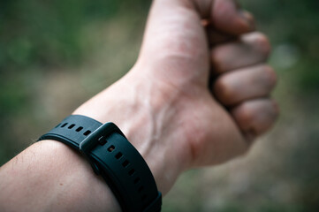 Black silicone watch band on Caucasian man's hand, close up, selective focus. Smartwatch bracelet.