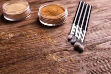 Loose compact mineral powder for face and a brushes for powder and visage on wooden background. Eco friendly and organic cosmetics.