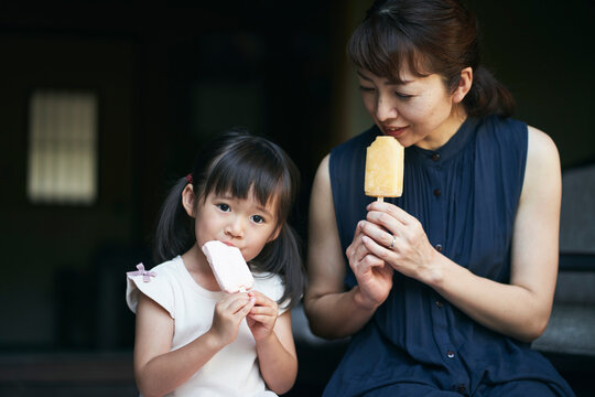 夏の縁側でアイスを食べる母と娘