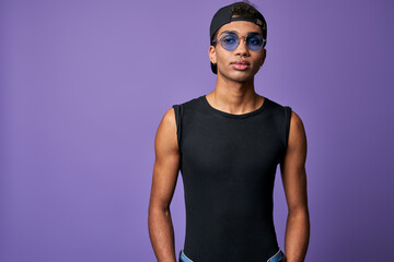 Horizontal portrait of young transgender man in black t-shirt, blue sunglasses. Latino trans gender