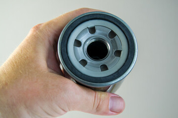 Hand holds a new car oil filter. engine oil cleaner