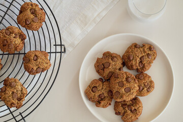chocolate chip cookies on a white plate with a glass of milk