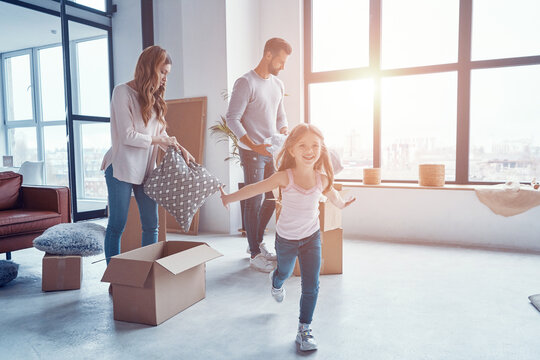 Happy young family smiling and unboxing their stuff while moving into a new apartment