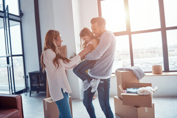 Cheerful young family smiling and bonding together while moving into a new apartment