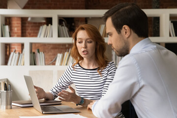 Discussion of new corporate app, business negotiations, sales manager showing to client online presentation concept. Young woman talk to colleagues sit at desk working together look at laptop screen