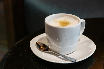 Cup of cappuccino coffee with soft microfoam on table.