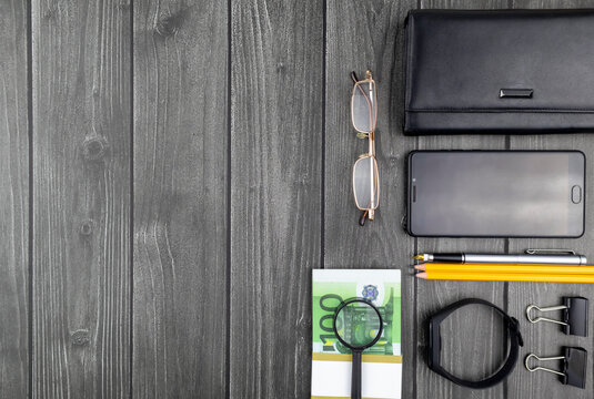 Office financial flat lay still life with 100 euro bills, purse, smartphone and stationery over a wood background with copyspace