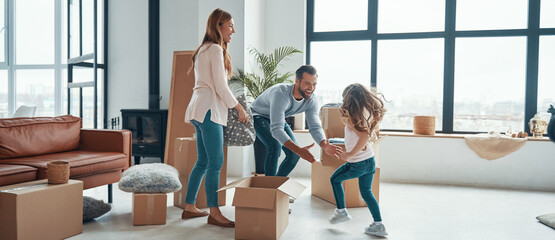 Happy young family smiling and unboxing their stuff while moving into a new apartment