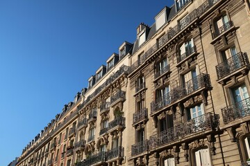 Fototapeta na wymiar Immobilier ancien dans la ville de Paris, alignement de façades d'immeubles haussmanniens avec balcons, sur fond de ciel bleu (France)