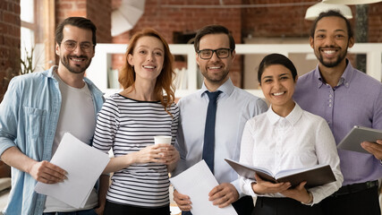 Team of diverse businesspeople multiethnic colleagues standing in modern office smile look at...