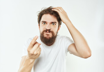 Naklejka premium emotional man in a white t-shirt hand gestures anger light background