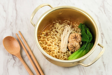 Korean Ramyeon on Gold Bowl, Serve with Shimeji Mushroom, Kimchi, and Half Boiled Egg on White Marble Table,