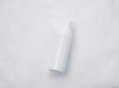 White plastic tube mockup with moisturizer cream, shampoo or facial cleanser and gentle soap foam with bubbles on marble background, top view. Treatment spa beauty skincare cosmetic product