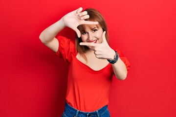 Redhead young woman wearing casual red t shirt smiling making frame with hands and fingers with happy face. creativity and photography concept.