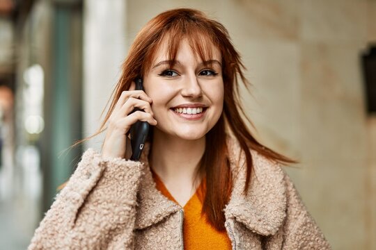 Young redhead girl smiling happy talking on the smartphone at the city.
