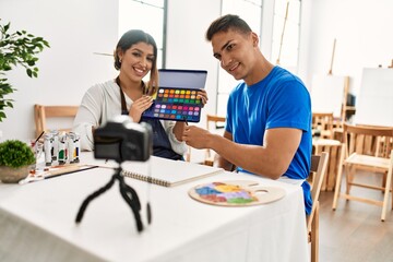 Two students smiling happy recording paint class using camera at art school.