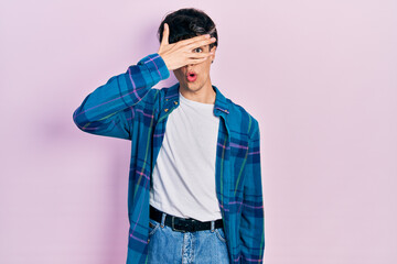 Fototapeta premium Handsome hipster young man wearing casual white t shirt and vintage shirt peeking in shock covering face and eyes with hand, looking through fingers with embarrassed expression.